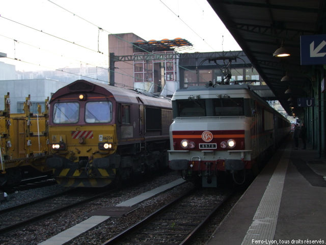 La CC 6570 et sa rame à quai en gare de Lyon-Perrache dépassée par un train de marchandises